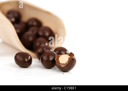 Ricoperta di cioccolato le nocciole su una paletta di legno Foto Stock