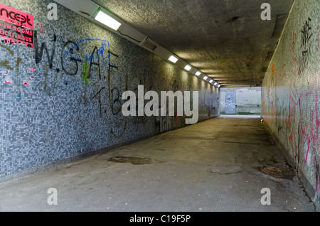 Immagine di un sottopassaggio pedonale, disseminato di spazzatura e coperto di graffiti pareti. Foto Stock