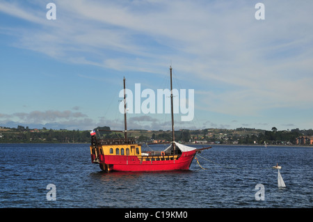 Cielo blu vista modello di yacht e dipinte di rosso galeone-come imbarcazione da diporto ormeggiato sulle acque del Lago Llanquihue, Puerto Varas, Cile Foto Stock