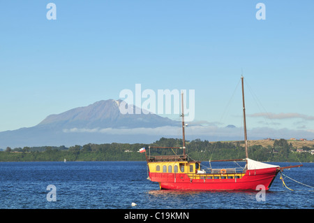 Cielo blu vista del galeone rosso-come imbarcazione da diporto ormeggiato sul Lago Llanquihue, verso Volcan Calbuco, da Puerto Varas, Cile Foto Stock