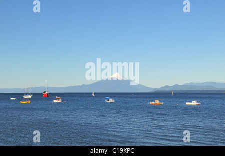 Cielo blu vista di piccole imbarcazioni ormeggiate sul Lago Llanquihue, guardando verso il cono di ghiaccio del Volcan Osorno, da Puerto Varas, Cile Foto Stock