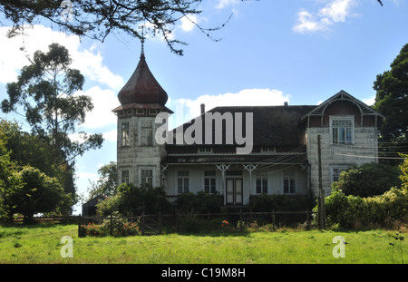 Cielo blu erba verde del giardino di una grande casa Chilean-German con scandole di bianco e torre decorativa, vicino Frutillar, Cile Foto Stock