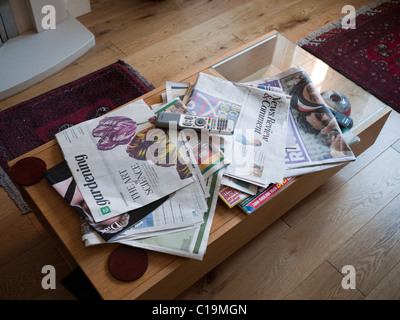 Quotidiani sparsi su un tavolo da caffè Foto Stock