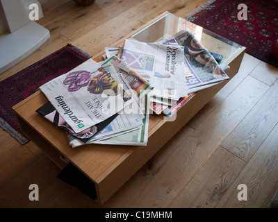 Quotidiani sparsi su un tavolo da caffè Foto Stock