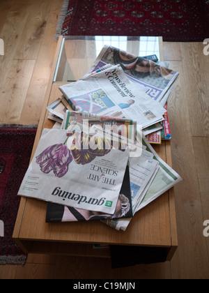 Quotidiani sparsi su un tavolo da caffè Foto Stock