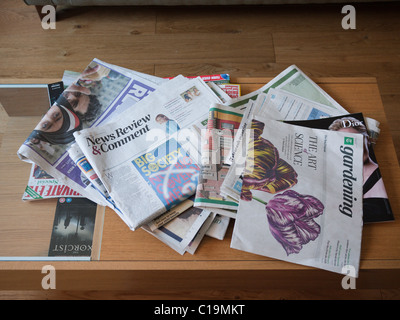 Quotidiani sparsi su un tavolo da caffè Foto Stock