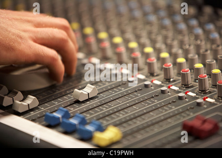 Cursori e tecnici del suono mano sul mixaggio audio scrivania in un teatro concert hall Foto Stock