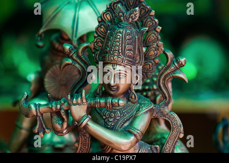 Statua metallica di dio indù Krishna suonare il flauto. Sul display shop, Puttaparthi, Andhra Pradesh, India del Sud. Foto Stock