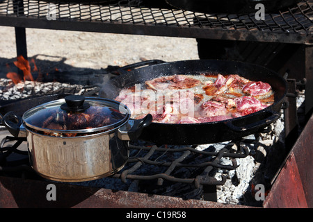 Bistecca di carne di montone costolette di agnello per la cottura in ghisa padelle su un aperto il fuoco all'aperto. Cowboy e pecore camp e barbecue party. Campfire. Foto Stock