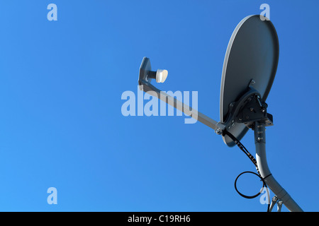 Un moderno HD antenna parabolica montata sul grigio di un palo metallico appuntito verso un cielo blu chiaro. Foto Stock