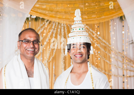 Sposo sorridente con il sacerdote in wedding mandap durante il matrimonio in Bengali Foto Stock