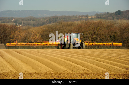 La spruzzatura di erbicida su un neo-piantati campo di patate, prima del rivestimento con il vello di proteggere contro le gelate tardive Foto Stock