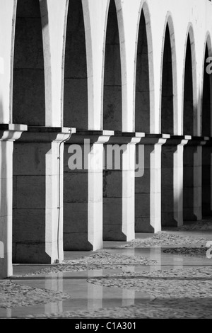 Vista di una strada urbana con tradizionale pavimentazione portoghese e alcuni archi di un edificio. Foto Stock