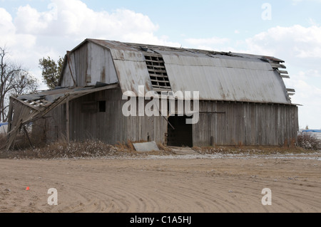 Fotografia di un vecchio fienile in Arkansas che necessitano di riparazione sabbiosa di primo piano con un cielo blu e i moduli di cotone in background Foto Stock