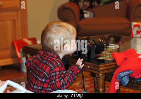 Ragazzo che guarda attraverso il mirino della fotocamera a Natale. Foto Stock