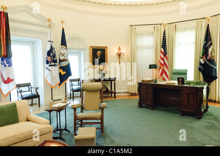 LBJ Library Oval Office Replica Interior | AUSTIN, Texas - Una replica Oval Office in scala reale presso la LBJ Library and Museum ricrea la stanza come l'ha usata il presidente Lyndon B. Johnson, completa di tappeto verde, scrivania presidenziale e un ritratto di George Washington sopra il tavolo della console. Johnson è stato il primo presidente a fare affidamento sull'Ufficio ovale come suo spazio di lavoro quotidiano, conducendo il suo famoso stile di lobbying personale "Johnson Treatment" da dietro quella scrivania. Le bandiere del servizio militare e il sigillo presidenziale fiancheggiano la stanza come nella disposizione originale della Casa Bianca. Foto Stock