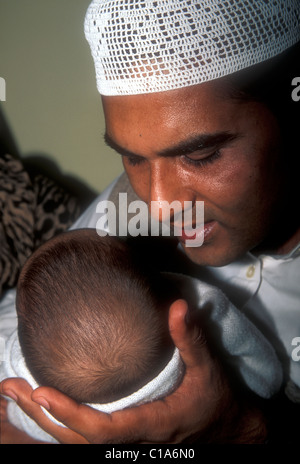 Il padre musulmano sussurra l'adhan, le parole di apertura della shahada, la dichiarazione della fede, nel suo bambino`s orecchio destro. Foto Stock