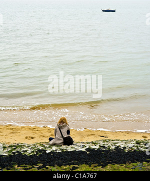 Una donna seduta sulla spiaggia di Southend. Fotografia di Gordon Scammell Foto Stock