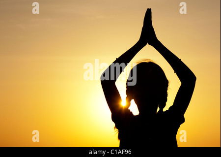 Ragazza indiana pregando al tramonto. Silhouette. India Foto Stock