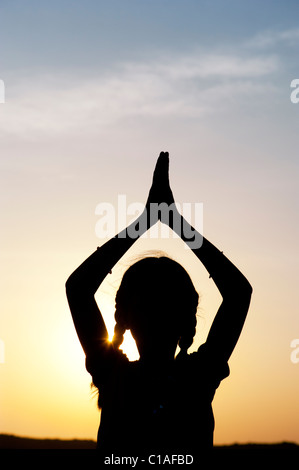 Ragazza indiana pregando al tramonto. Silhouette. India Foto Stock