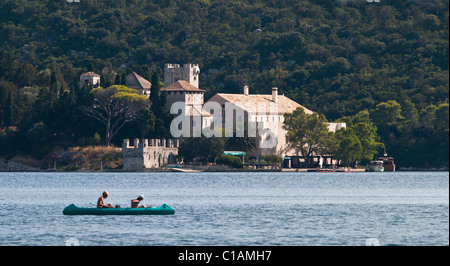 L'immagine mostra un paio di godere in un kayak e una del XII secolo il monastero, situato su una piccola isola . Foto Stock
