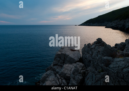 Il tramonto. Rocciose scogliere calcaree circondano bellissima costa del mare adriatico Foto Stock