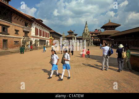 Studentesse attraversando a piedi il quadrato di Durbar nel sito Patrimonio Mondiale dell'UNESCO, la città di Bhaktapur, Valle di Kathmandu, Nepal, Asia Foto Stock