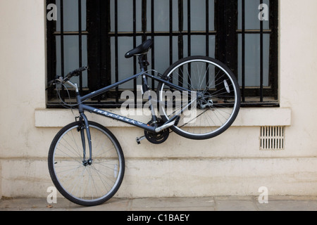 Una bicicletta incatenato al lato di un edificio nel centro commerciale della città di Londra Inghilterra Foto Stock