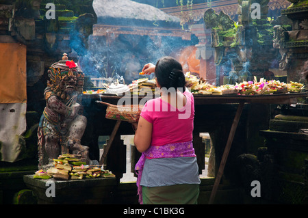 Donna fare mattina offerte presso il tempio occupato vicino al mercato principale di Ubud Foto Stock