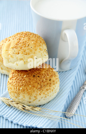 Panini freschi con semi di sesamo e un bicchiere di latte prima colazione Foto Stock