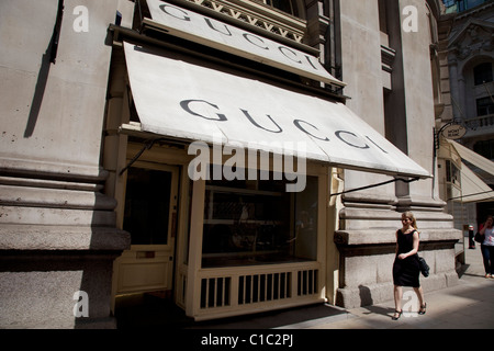 La donna in un abito nero passeggiate oltre il negozio di Gucci in Cornhill nella città di Londra. Foto Stock
