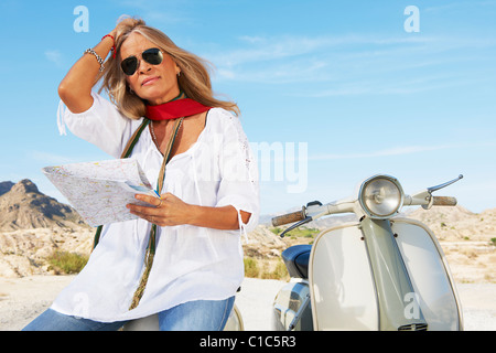 Donna seduta su moto con mappa Foto Stock