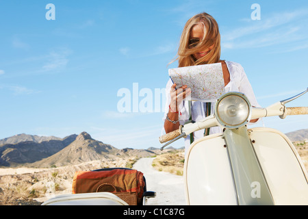 Donna seduta su moto con mappa Foto Stock