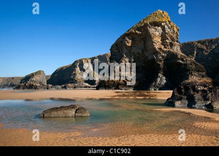 Una vista di una roccia di pile sulla spiaggia di Bedruthan Steps in Cornwall Regno Unito con sabbia e acqua piscine in primo piano Foto Stock