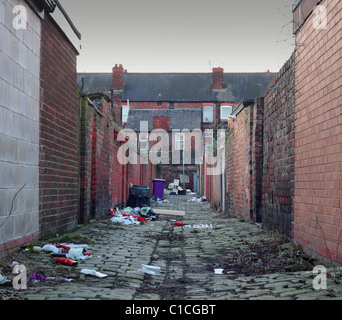 Rifiuti domestici lasciati circa in una sporca back street di ciottoli lapidato alley Foto Stock