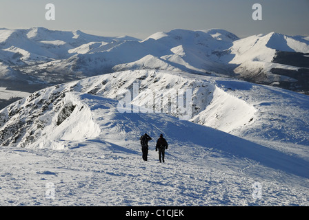 Walkers sul crinale del vertice della coperta di neve Blencathra in inverno nel Lake District inglese. Derwent Fells in background Foto Stock