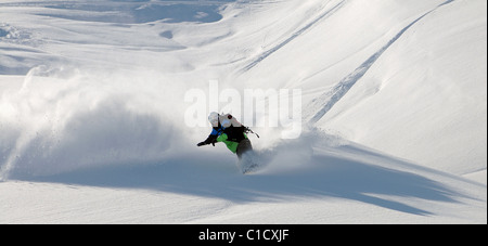 Uno snowboarder intaglia un giro nella neve profonda i fuori pista in Les Avals area della località sciistica di Courchevel nelle Alpi francesi. Foto Stock