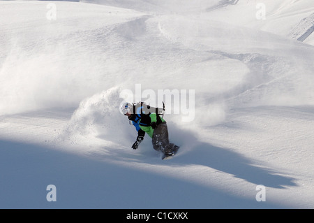 Uno snowboarder intaglia un giro nella neve profonda i fuori pista in Les Avals area della località sciistica di Courchevel nelle Alpi francesi. Foto Stock