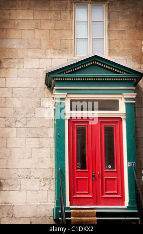 Un audace porta rossa insieme contro un vecchio muro di pietra della Vecchia Montreal, Quebec. Foto Stock