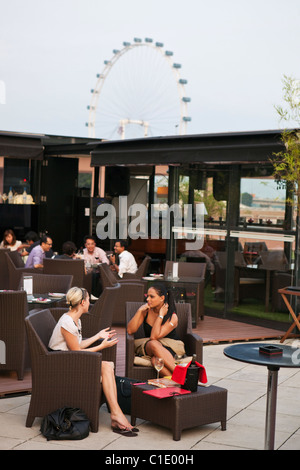 Le donne di bere a Orgo Bar & Ristorante con Singapore Flyer in background. Il Marina Bay, Singapore Foto Stock