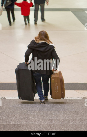 Ragazza donna portare 2 portante due valigie gradini scale Foto Stock