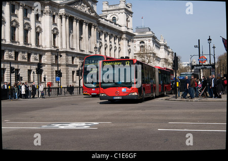 Un bus articolato passato Westminster stazione della metropolitana come esso lascia il Parlamento Street girare a sinistra verso Westminster Bridge Foto Stock