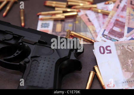 Una scorta di farmaci di pistola e il denaro che mostra un costo pericolose per la vita contro uno sfondo scuro Foto Stock