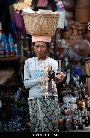 Un gingillo venditore al Ubud Mercato Pubblico di Bali, Indonesia guarda la speranza che una vendita è proprio dietro l'angolo. Foto Stock
