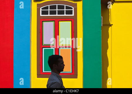 Uomo che cammina passato un variopinto edificio storico in Little India, Singapore Foto Stock