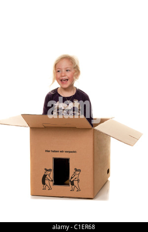 Bambino in una scatola di cartone. Si trova nella scatola quando si muove. Foto Stock