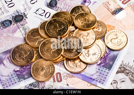 Un mucchio di krugerrand sulla sterlina note Foto Stock