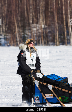 Musher Kristy Berington competere nel trentanovesimo sentiero Iditarod Sled Dog Race sul lungo lago dopo aver lasciato Willow Lago di riavviare. Foto Stock