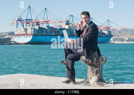 Imprenditore ispanica holding portatile con nave portacontainer in background Foto Stock