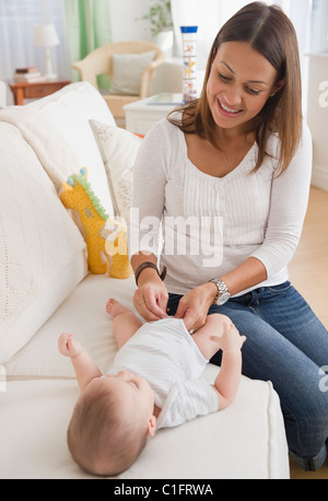 Cambiando la madre del bambino pannolino sul divano Foto Stock